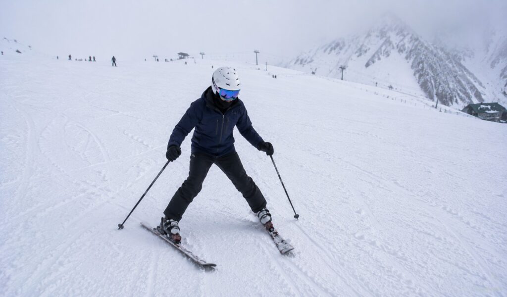 Beginner skier linking turns on a nursery slope
