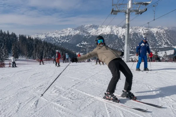 A beginner skier struggling with backseat stance on a nursery slope