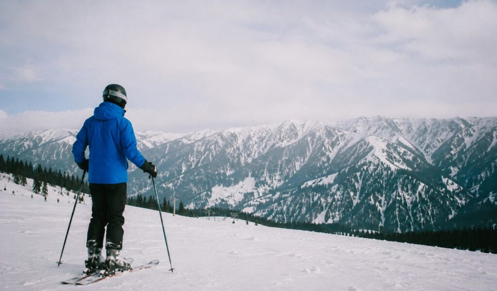 Everyday traveler standing on a snowy mountain slope looking out at the Gulmarg winter ski resort mountains.