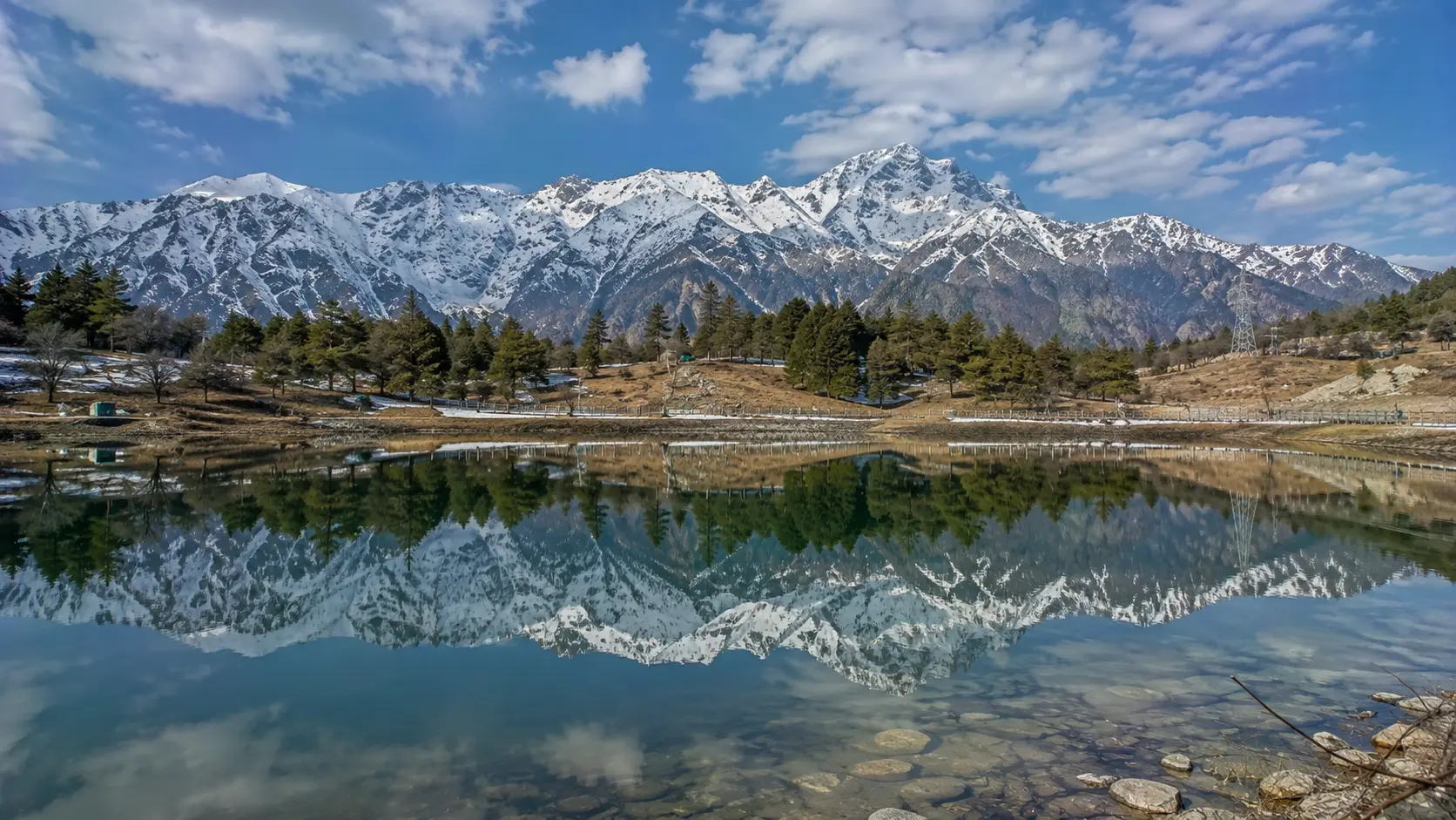 Scenic view of snow-capped Himalayan peaks reflecting in a pristine valley lake, representing Travinfo's Himalayan adventure travel guides.
