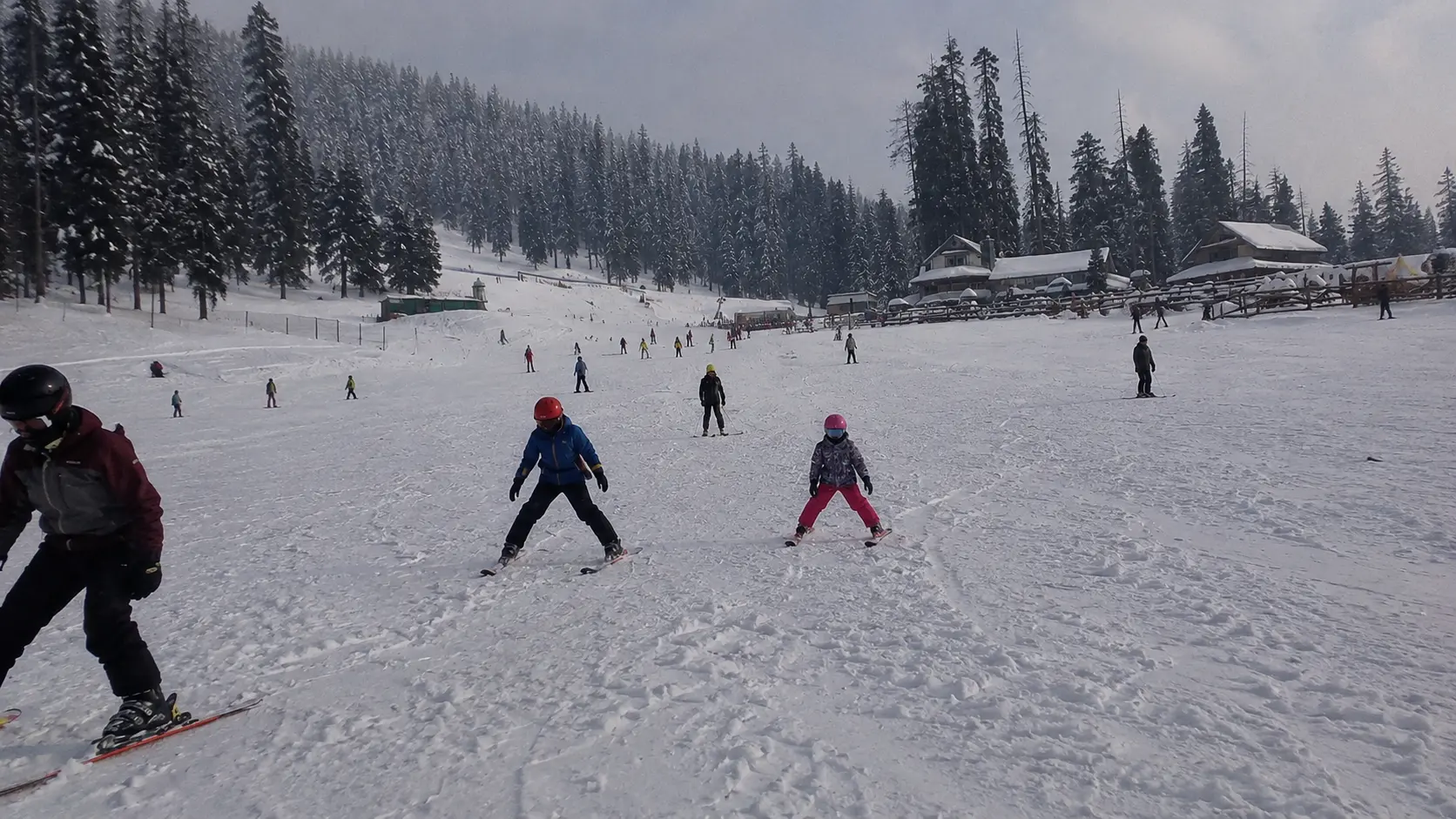 Ski students practicing basic snowplough stance drills on the nursery slopes in Gulmarg